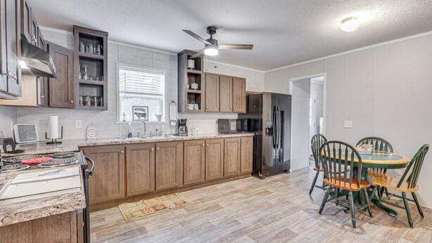 A modern kitchen with wooden cabinets, a built-in microwave, and a dining area with a table and chairs. - Pet-friendly Home ~ 10 Mi to Hocking Hills! (Laurelville)