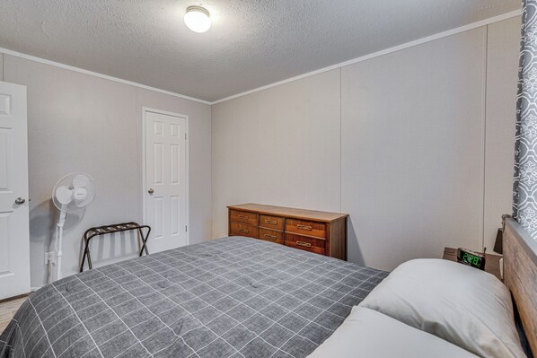 Un dormitorio con una cama, un tocador, un ventilador y una puerta.