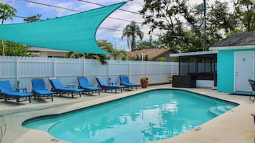 A swimming pool with blue lounge chairs and a white fence.