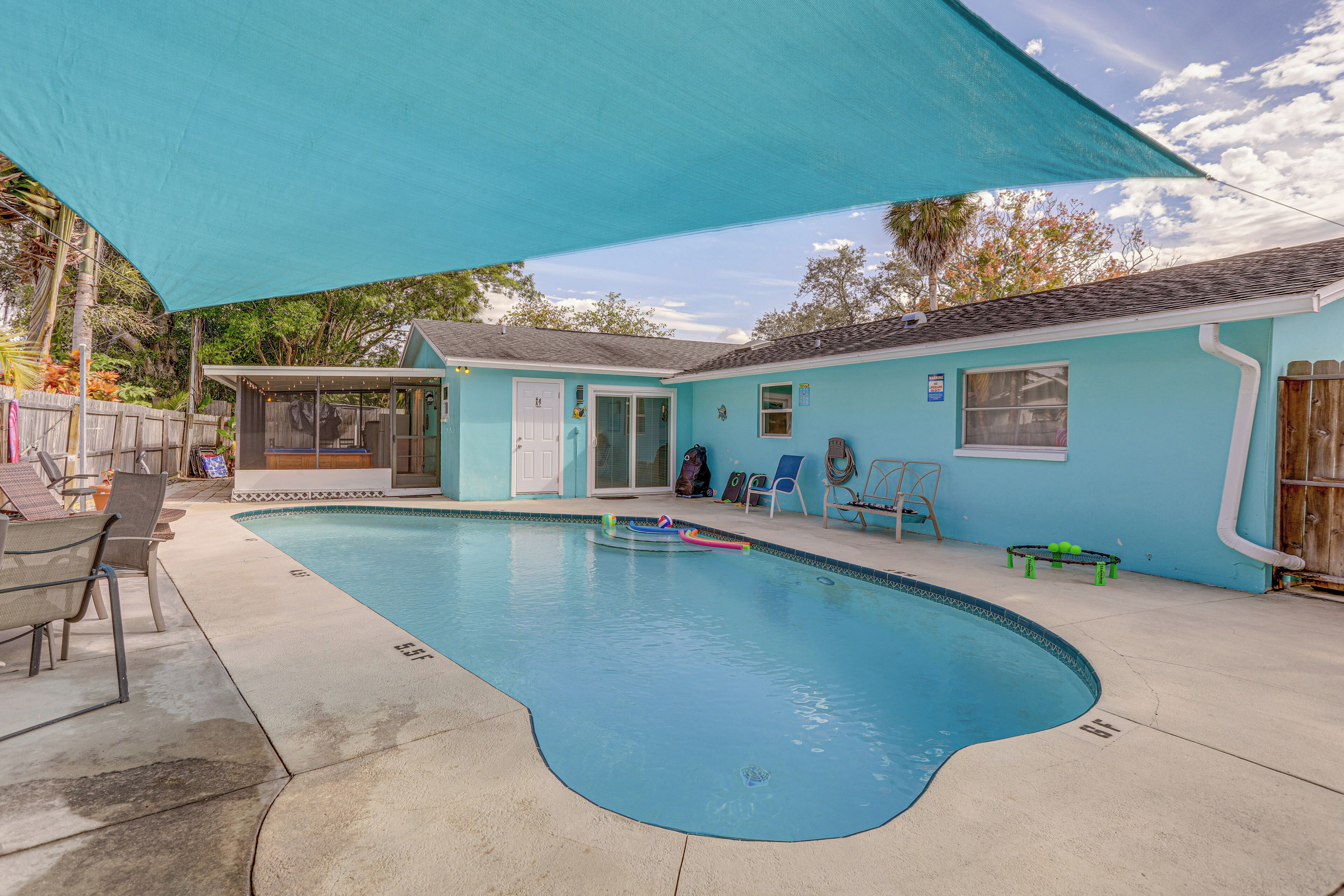 A swimming pool with a covered patio area, a small house, and outdoor seating.
