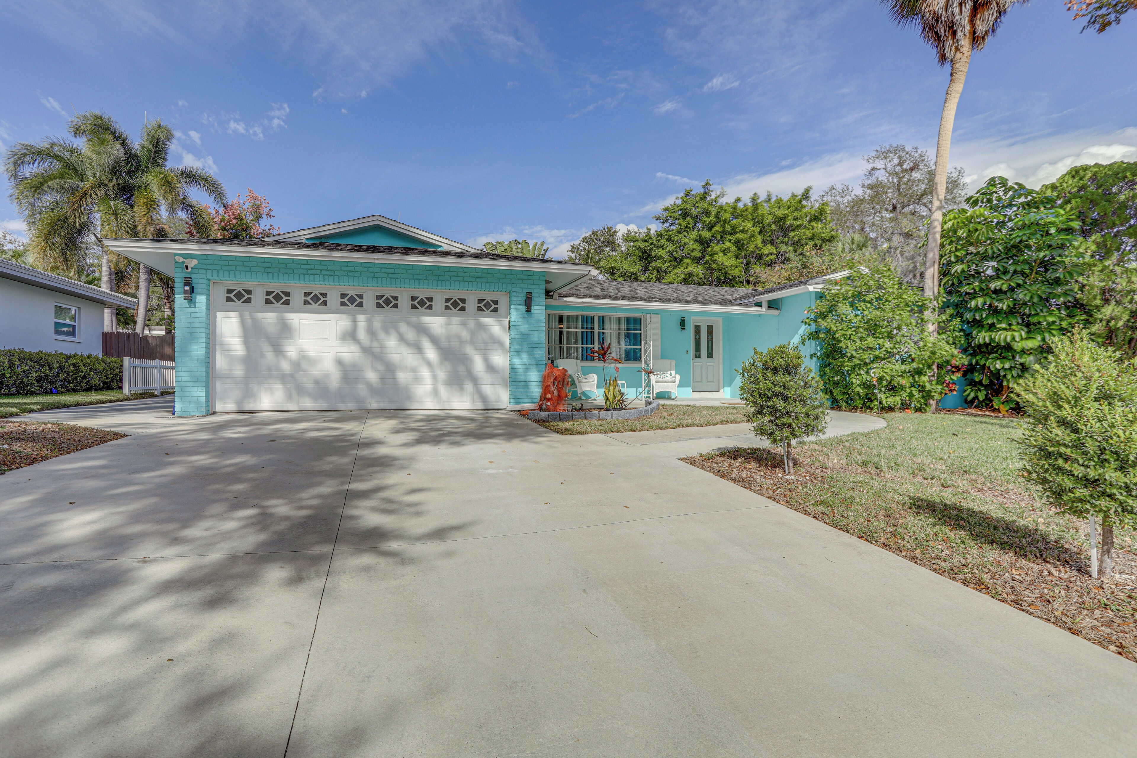 A single-story house with a garage, a front porch, and a small front yard with a palm tree and shrubs.