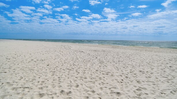 A wide sandy beach with footprints leading to the water. - Family-friendly Pensacola Home < 1 Mi to Beach! (Pensacola)