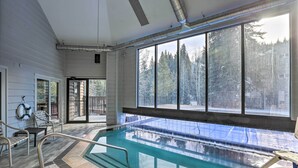Piscina con vista a árboles y un área de terraza cubierta.