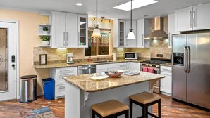 A modern kitchen with white cabinets, a granite countertop, stainless steel appliances, and a central island with stools. - 1 Mi to Trails: Pet-friendly Home in West Sedona! (Sedona)