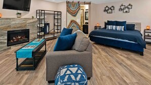 A modern living room with a fireplace, a sofa, a bed, and a TV mounted on the wall. - 1 Mi to Trails: Pet-friendly Home in West Sedona! (Sedona)