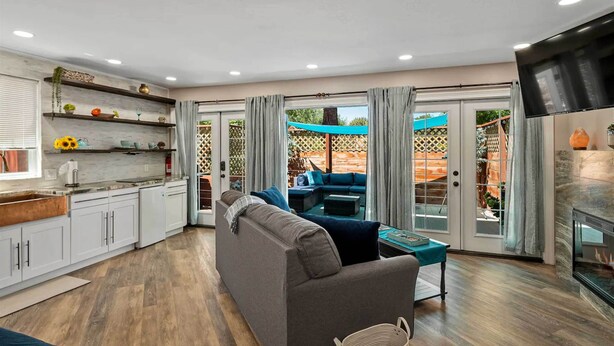 A modern kitchen with white cabinets, a grey sofa, and a dining area with a blue table. - 1 Mi to Trails: Pet-friendly Home in West Sedona! (Sedona)