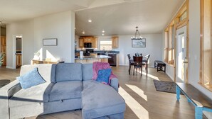 A spacious living room with a large sectional sofa, a dining area with a wooden table and chairs, and a kitchen in the background. - Peaceful Deary Vacation Rental w/ Deck & Views! (Deary)