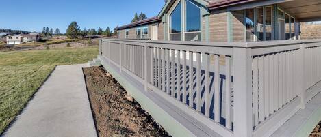A modern house with a covered porch, a concrete pathway, and a fenced yard.