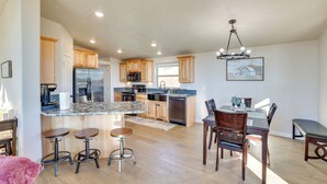 A spacious kitchen with wooden cabinets, a stainless steel refrigerator, and a marble island with bar stools. - Peaceful Deary Vacation Rental w/ Deck & Views! (Deary)