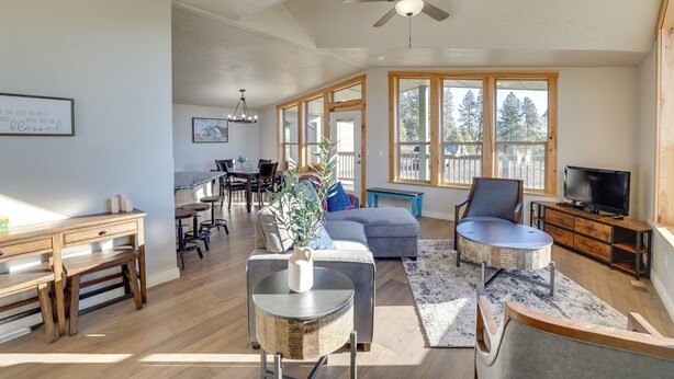A spacious living room with a dining area, large windows, a ceiling fan, and a television. - Peaceful Deary Vacation Rental w/ Deck & Views! (Deary)