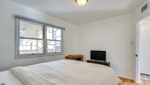 Ein Schlafzimmer mit einem großen Bett, einem Fernseher auf einem Schrank, einem Fenster und einer Tür.