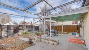 Ein überdachter Patio-Bereich mit einer Pergola, Sitzgelegenheiten im Freien und einem Steingarten.