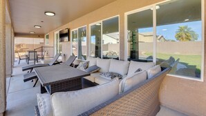 Ein überdachter Patio-Bereich mit Esstisch, Stühlen und einer Couch.