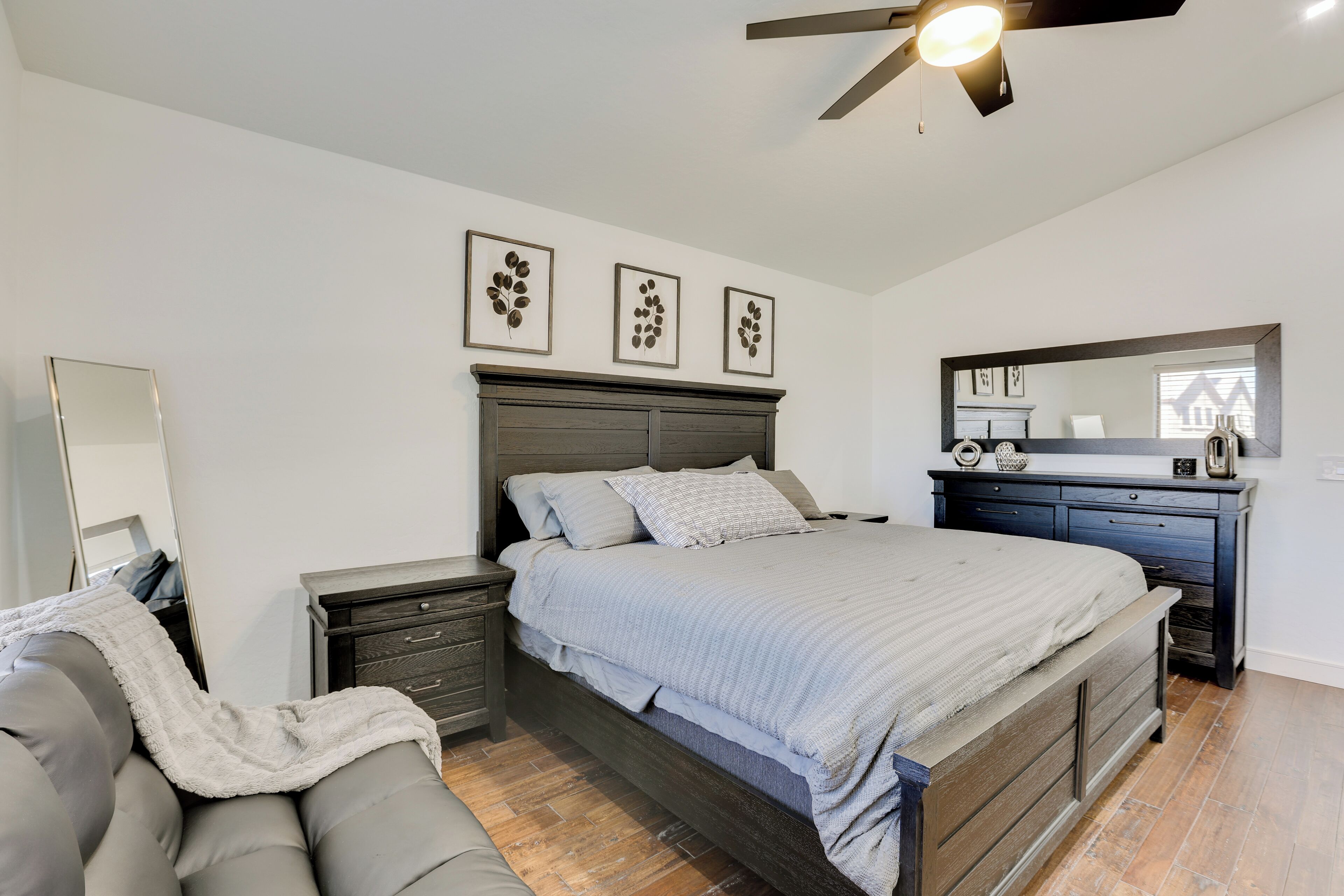 A bedroom with a bed, nightstands, a dresser, and a ceiling fan.