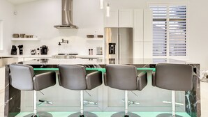 Eine moderne Küche mit Kochinsel, Edelstahlgeräten und Barhocker.