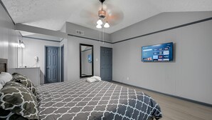 A modern bedroom with a bed, a flat-screen TV mounted on the wall, and a ceiling fan. - New Listing/NASA/ 4br 2ba 2000sq Sleeps10, Pet Friendly,Monthly discounts (League City)