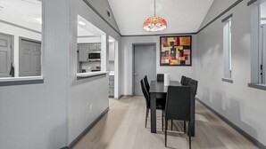 A modern kitchen with grey cabinetry, a dining area with a black table and chairs, and a colorful abstract painting on the wall. - New Listing/NASA/ 4br 2ba 2000sq Sleeps10, Pet Friendly,Monthly discounts (League City)