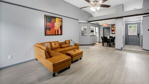 A spacious living room with a large sectional sofa, a ceiling fan, and a dining area with a table and chairs. - New Listing/NASA/ 4br 2ba 2000sq Sleeps10, Pet Friendly,Monthly discounts (League City)