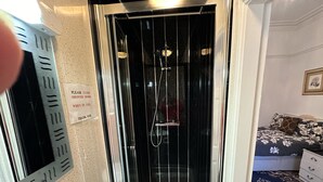 A shower with a sign instructing to close the door when in use. - Ocean Road Rooms (South Shields)