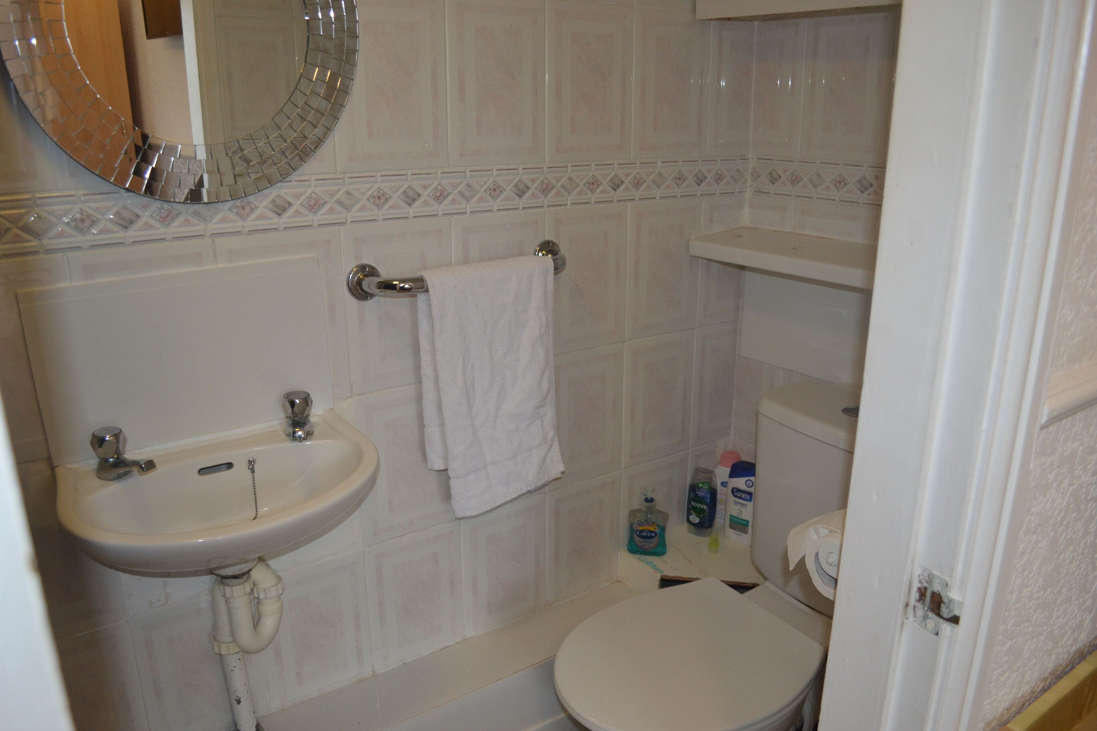 Une salle de bain avec un lavabo, un miroir, des toilettes et une serviette accrochée au mur.