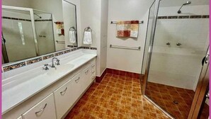 Een badkamer met een douche, een wastafel en een spiegel.