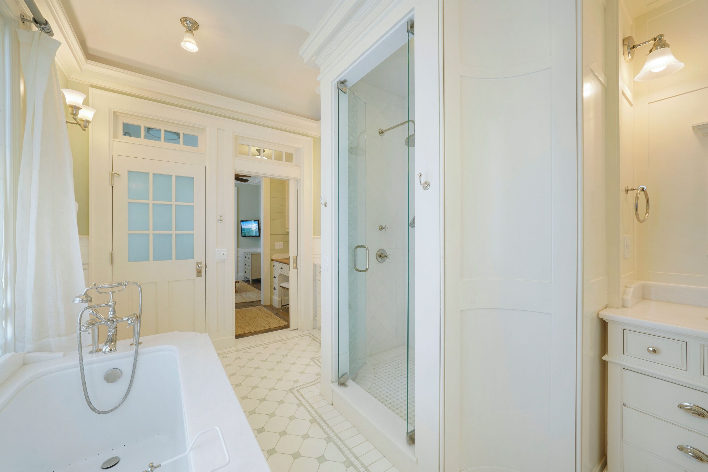 A modern bathroom with a glass-enclosed shower, a large bathtub, and a vanity with drawers.