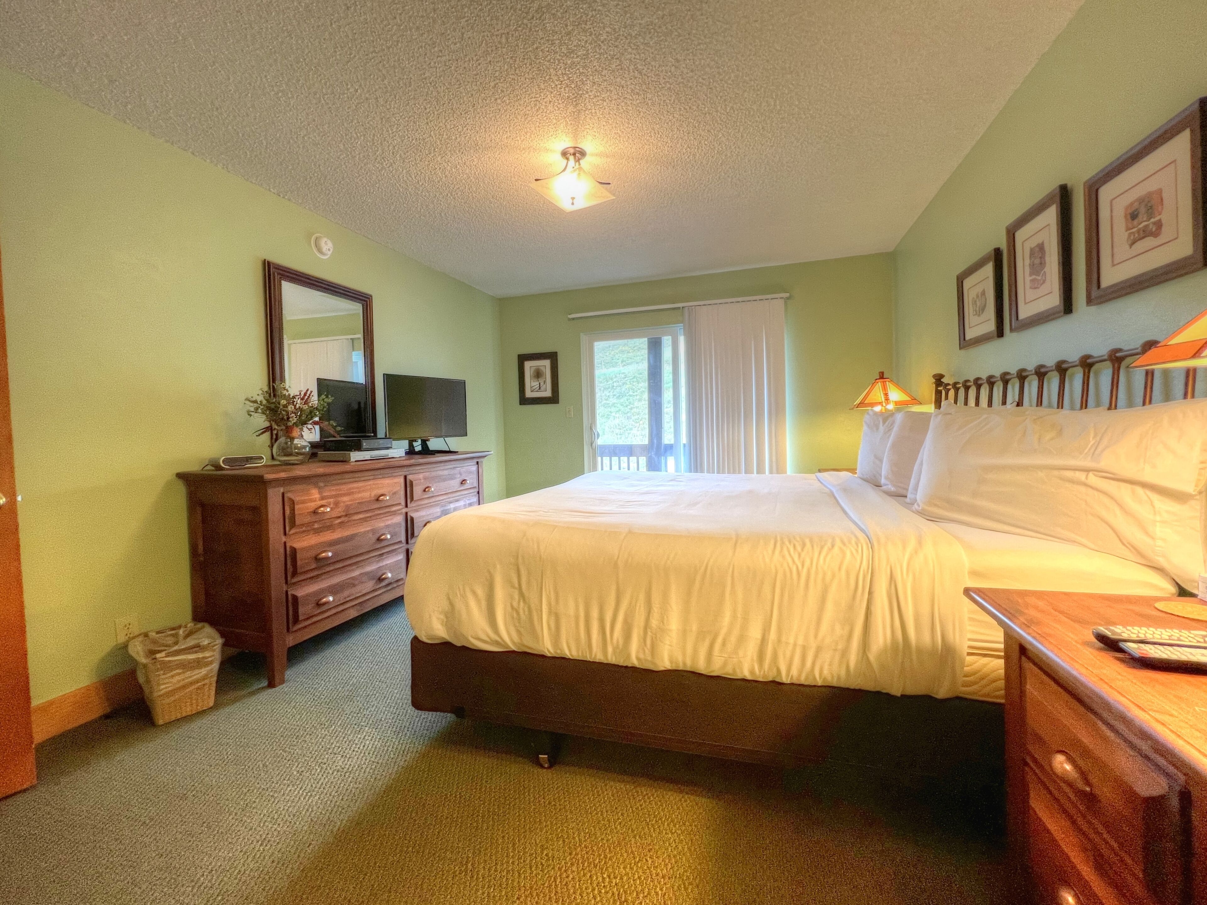 A bedroom with a bed, dresser, and a television on the dresser.