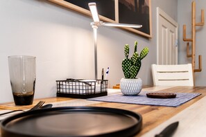 A dining table with a black tray, a glass of dark liquid, a cactus plant, a white chair, and a floor lamp.