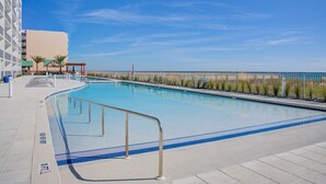 A swimming pool with a clear view of the ocean, a covered seating area, and a building with a modern design. - Luxury Beachfront Bliss – Blu’s Only 2BR Condo! (Fort Walton Beach)