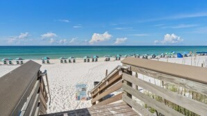 A beach with wooden walkways, beach umbrellas, and lounge chairs. - Luxury Beachfront Bliss – Blu’s Only 2BR Condo! (Fort Walton Beach)