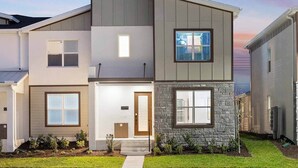 A modern two-story residential building with a stone accent wall, a front entrance with steps, and a visible mailbox. - Villa Palazzo | Perfect getaway w/ a PVT pool, huge BRs & suites, near top parks (Orlando)
