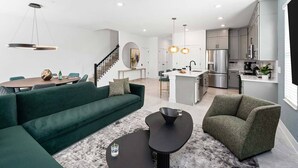 A modern living room with a green sofa, two black coffee tables, and a grey rug. - Villa Bellisima | Huge I-Drive villa w PVT pool, grand BRs, luxe LR, near parks (Orlando)