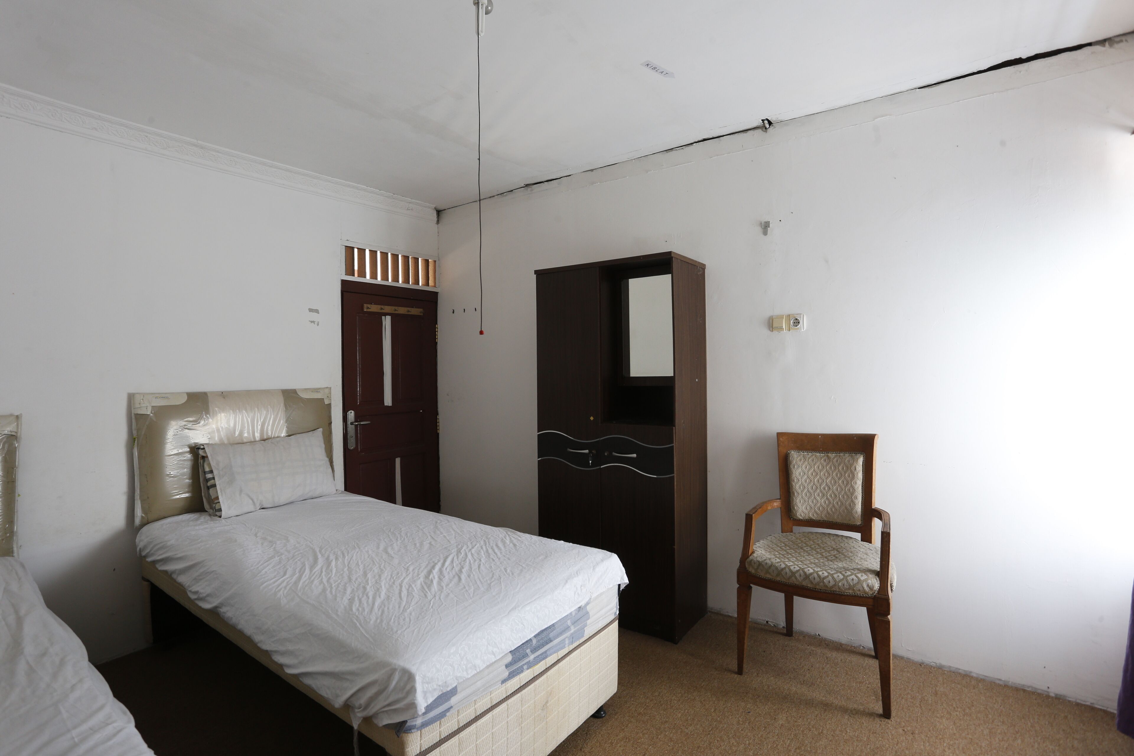 A bedroom with a bed, a wardrobe, and a chair.