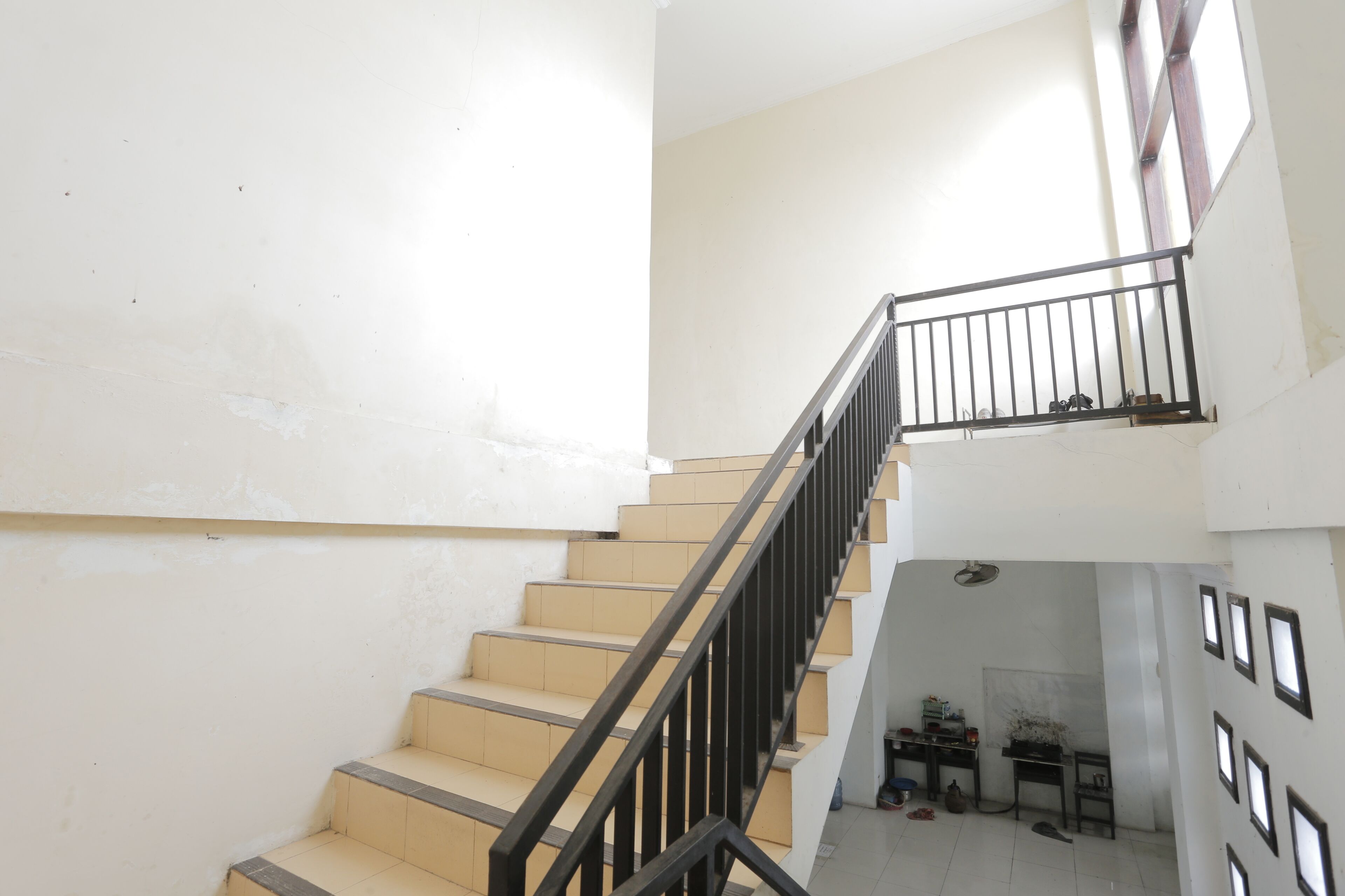 A staircase with beige steps and black railings, leading to a landing with a small table and chair.