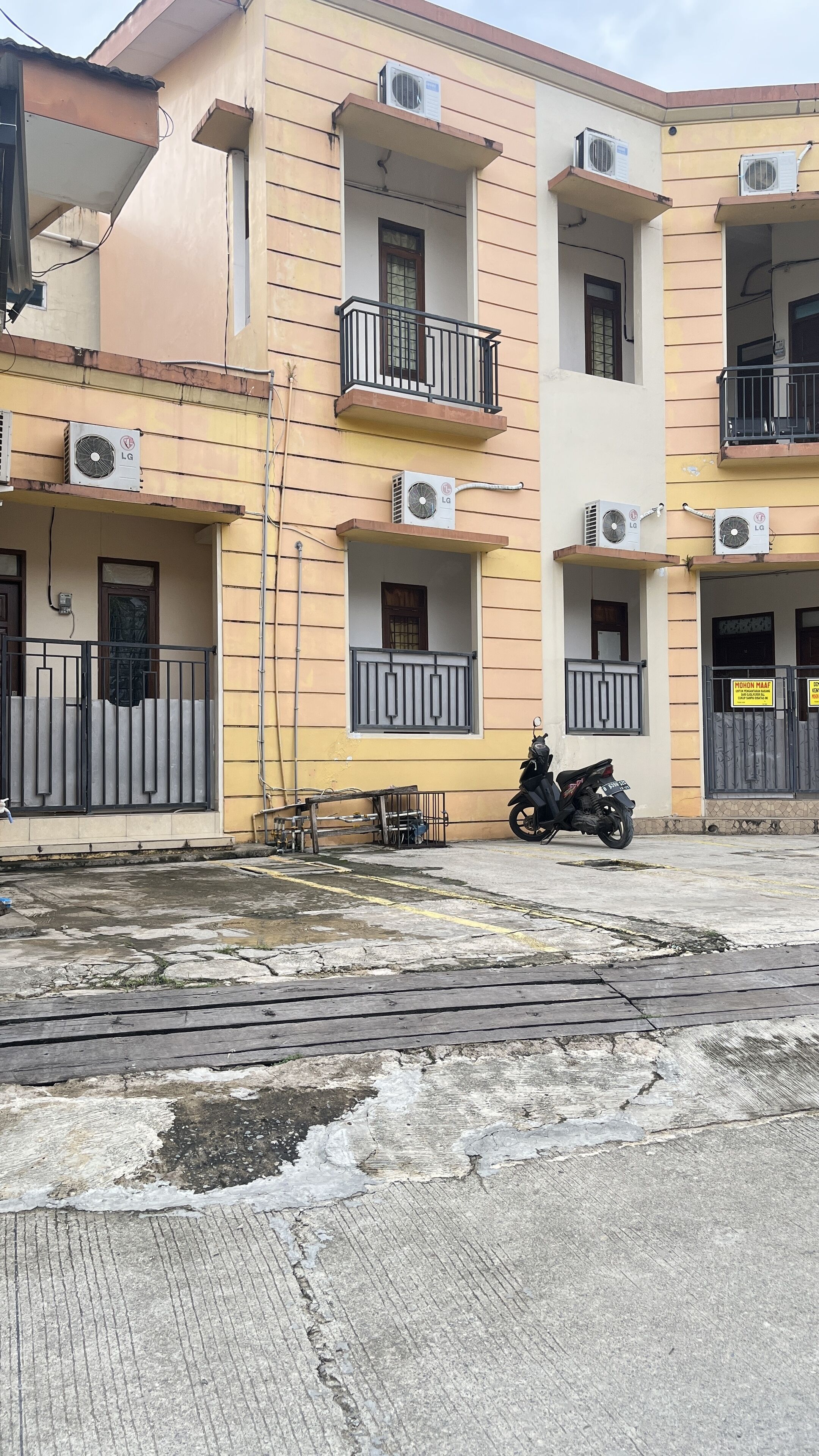 A multi-story residential building with balconies, air conditioning units, and a gated entrance.