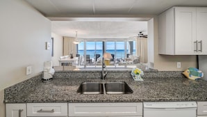 A kitchen with a granite countertop, double sink, and white cabinets. - FREE Beach Service, Golf &Perks! Long Beach Tower 3-303, Hot Tub, Gym & Pools (Panama City Beach)