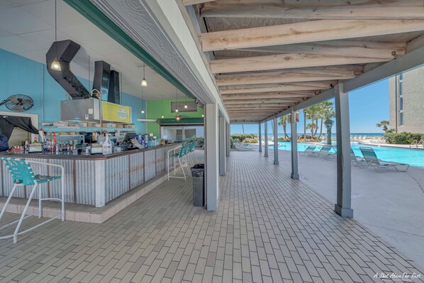 A covered outdoor area with a pool, bar, and seating.