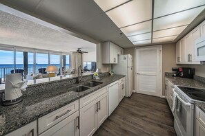 A modern kitchen with granite countertops, stainless steel appliances, and a view of the ocean. - FREE Beach Service, Golf &Perks! Long Beach Tower 3-303, Hot Tub, Gym & Pools (Panama City Beach)