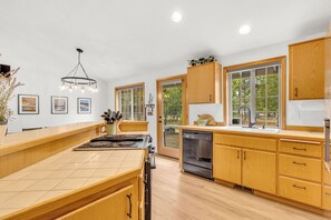 A modern kitchen with wooden cabinets, a central island, and a built-in dishwasher.