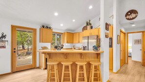 Una cocina moderna con armarios de madera, una isla central con taburetes y un refrigerador.