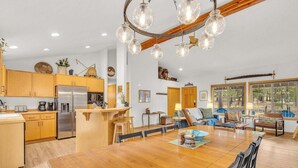 Una cocina amplia con armarios de madera, un refrigerador de acero inoxidable y un comedor con mesa y sillas de madera.