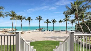 A beach view with palm trees and a pier. - Pineapple Beach (Islamorada)