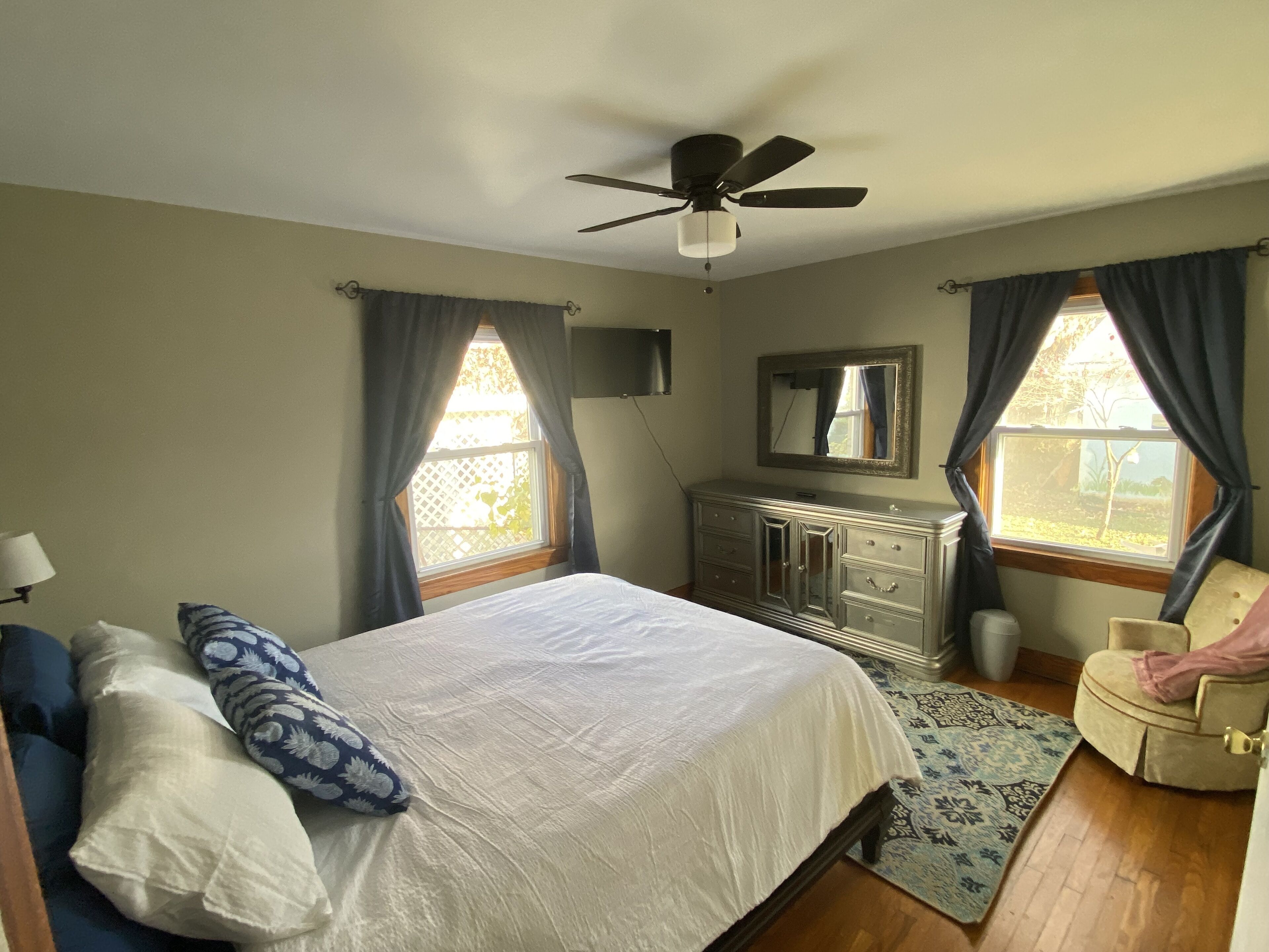 A bedroom with a bed, dresser, and chair.