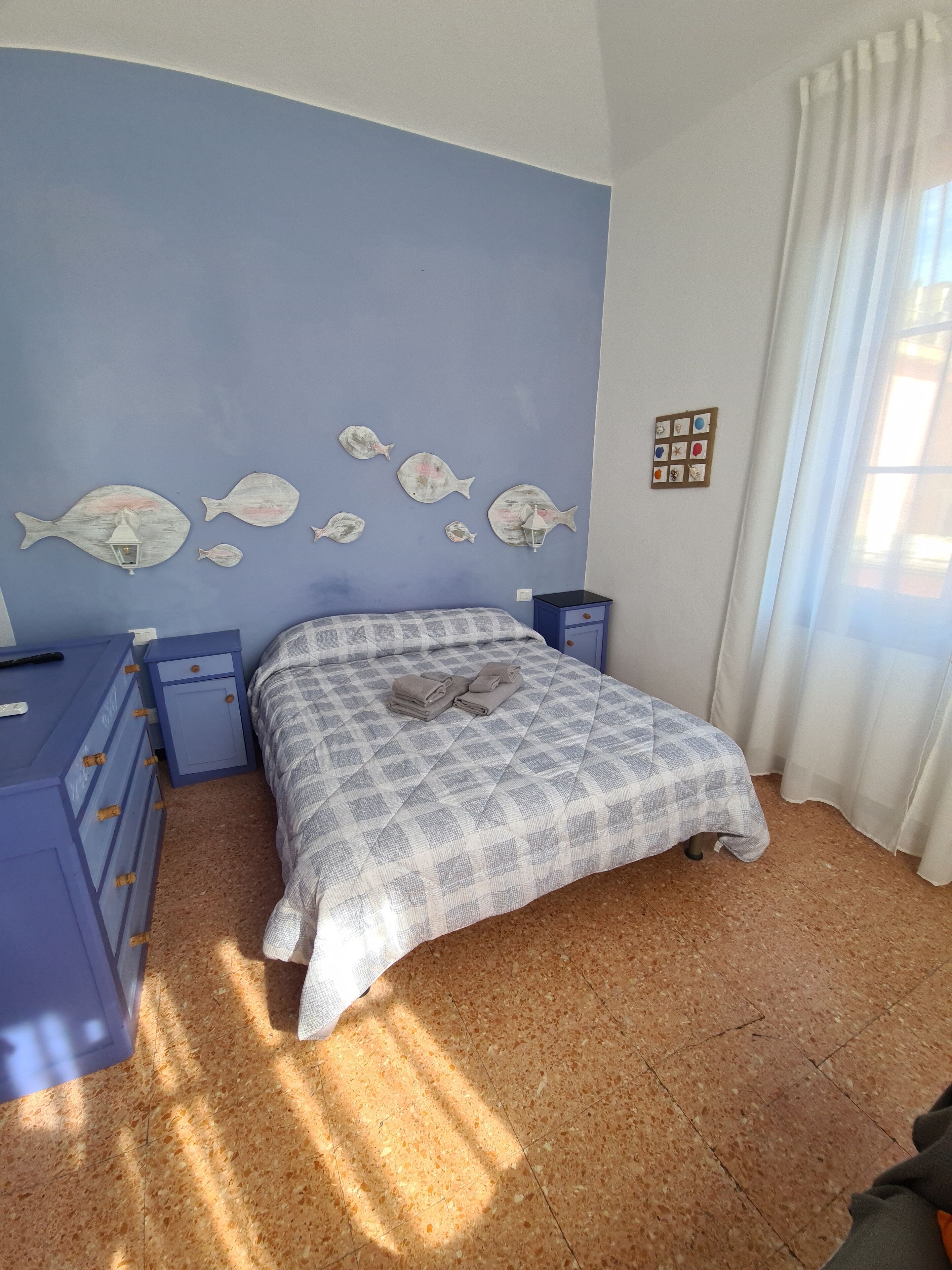 Une chambre à coucher comprenant un lit, des tables de chevet, une commode et des œuvres d’art murales.