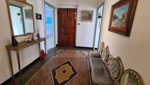 A hallway with a wooden door, a console table with a mirror, and a patterned rug. - Violetta Portofino by PortofinoVacanze  (Rapallo)