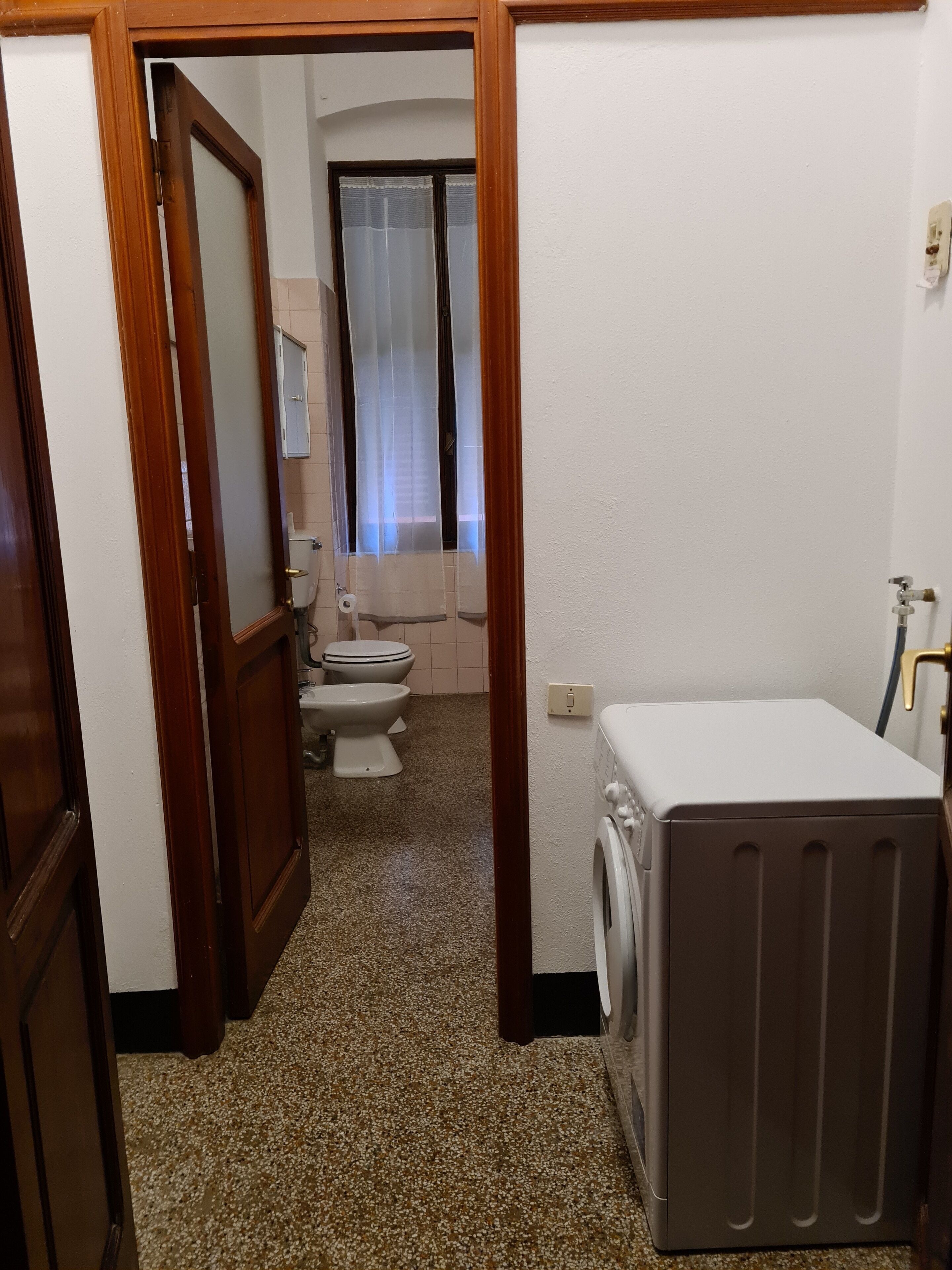 A compact bathroom with a toilet, bidet, and a washing machine.