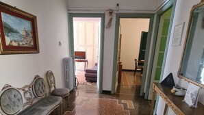 A hallway with a bench, a framed picture, a radiator, a mirror, and a fire extinguisher. - Violetta Portofino by PortofinoVacanze  (Rapallo)