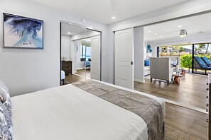 A modern hotel room with a large bed, a view of the balcony, and a painting on the wall.