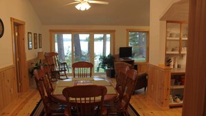 A dining area with wooden chairs, a table, and a ceiling fan. - Charming cottage with stunning views and 180' of waterfront on Little Sebago. (Gray)