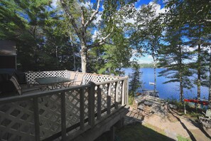 Una terraza de madera con mobiliario exterior con vistas a un lago.